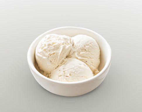 Eine Schüssel mit drei Kugeln vanillefarbenem Eis.