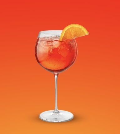 Ein Cocktailglas mit einem bunten Getränk und einer Orangenscheibe.