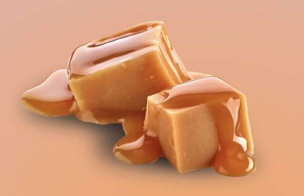 Karamellstücke mit glänzender, flüssiger Karamellsoße auf einem hellen Hintergrund.