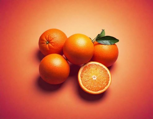 Fünf Orangen auf einem orangefarbenen Hintergrund, eine halbierte Orange sichtbar.