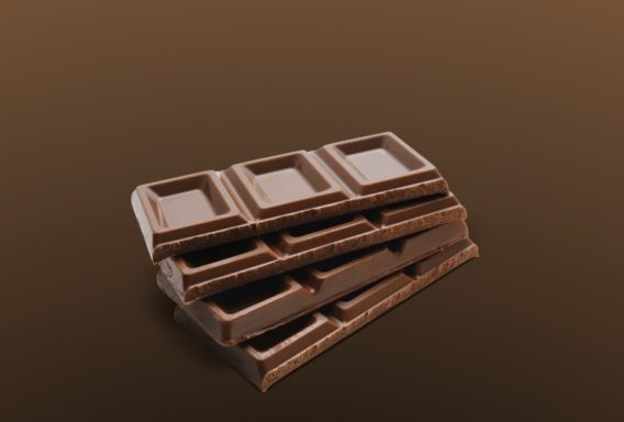 Dunkle Schokolade in einer gestapelten Anordnung auf einem braunen Hintergrund.