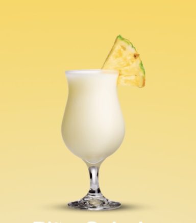 Ein Cocktail im Glas mit einer Ananasscheibe, auf gelbem Hintergrund.